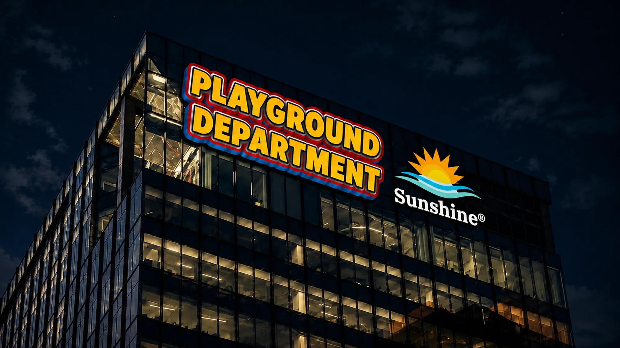 A glass office tower at night with the Playground Department and Sunshine® logos lit up across the top floors